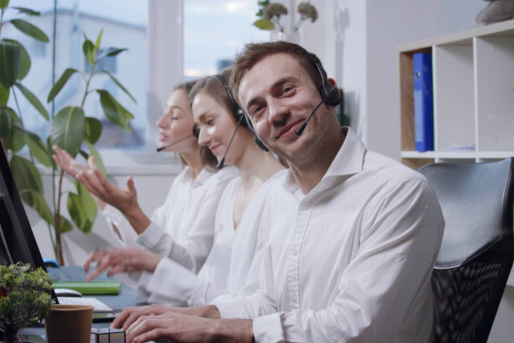 mad laughing and hilariously typing the keyboard, male operator looks straight to camera