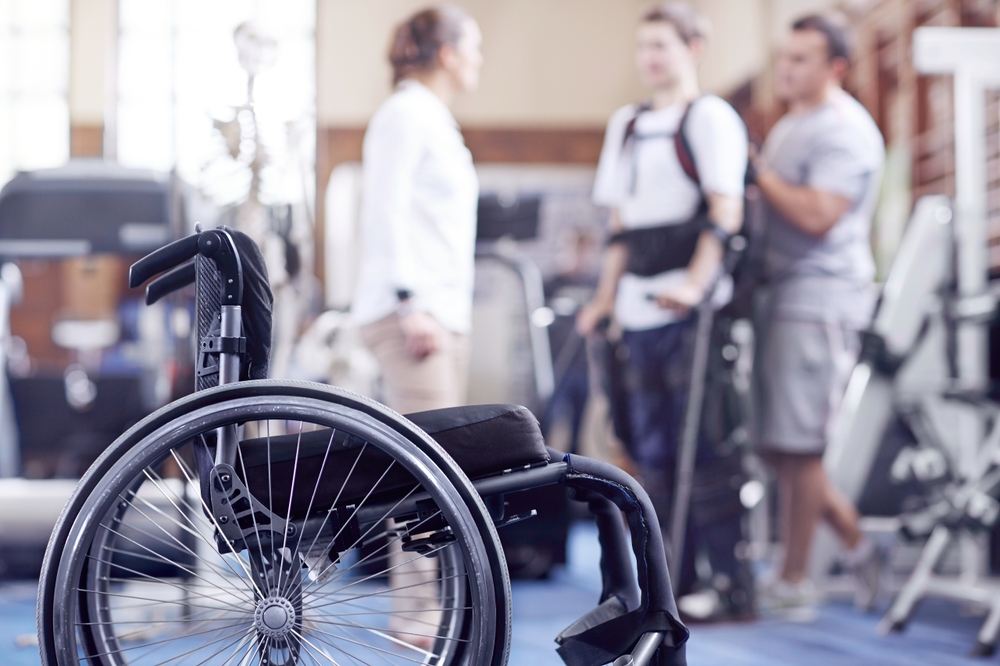 Man receiving physical therapy with wheelchair in foreground